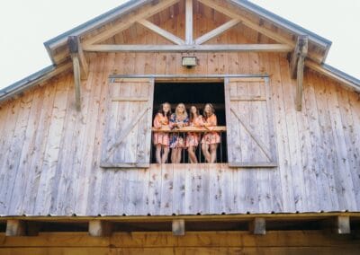 A bride and her maids of honor look out a windows inside The Barn at Stony Creek Farm in Dungannon, Virginia.