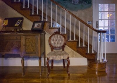 A staircase flanked by antique furniture inside Estillville Bed and Breakfast.