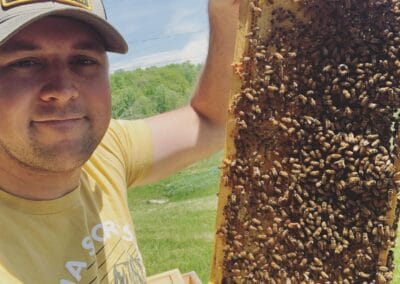 A man holding up a hive of bees at Hive and Honey, LLC.