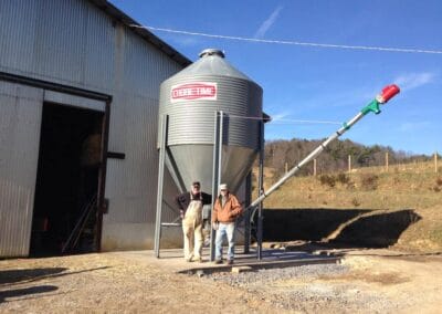 Two farmers standing in front of a feed bin at Pendleton Farms.