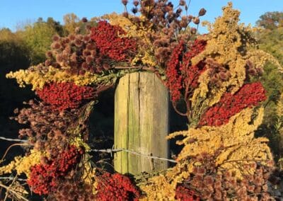 A wreath hanging on top of wooden fence post.